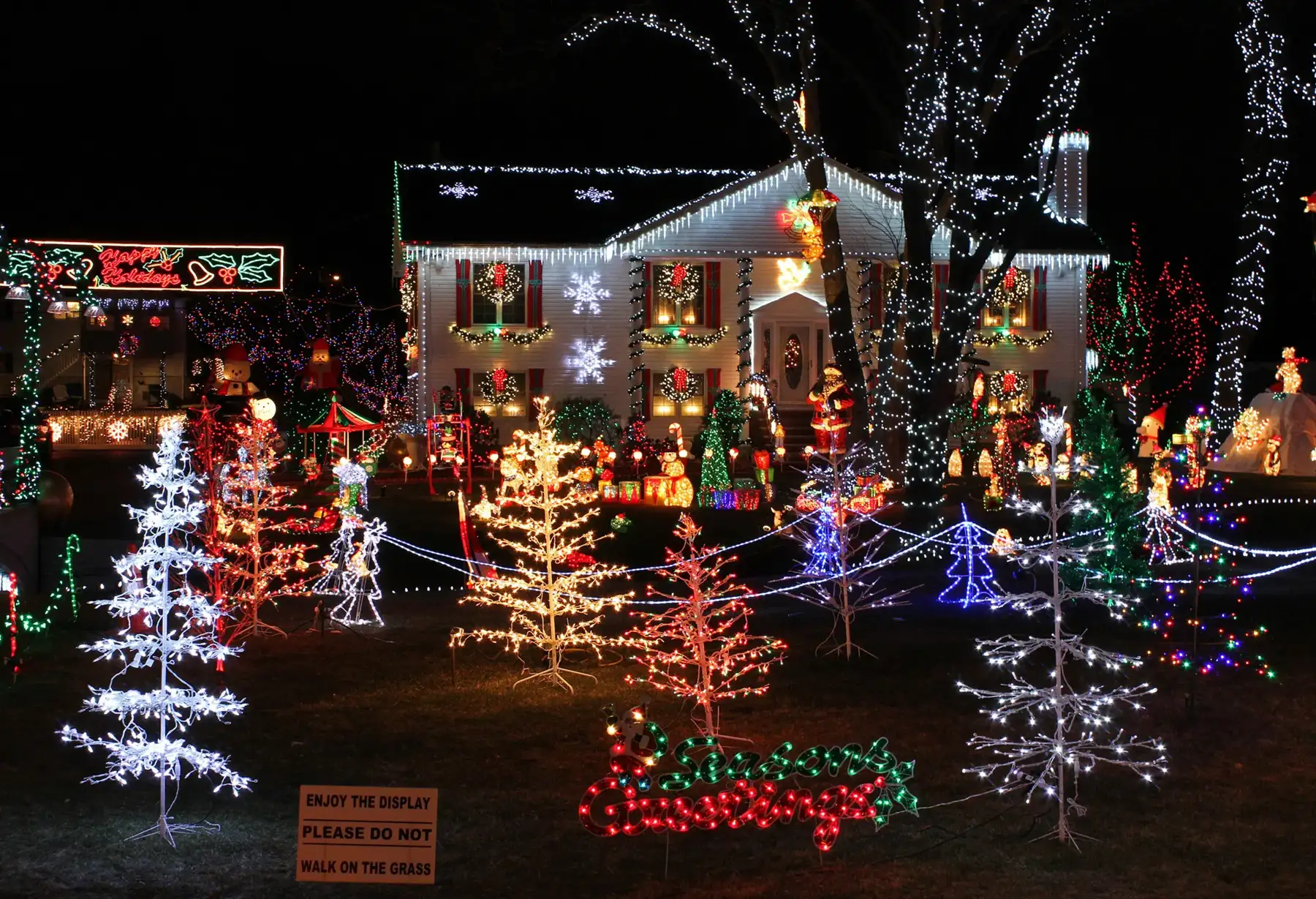 Front yard lit with Christmas lights and light-up trees